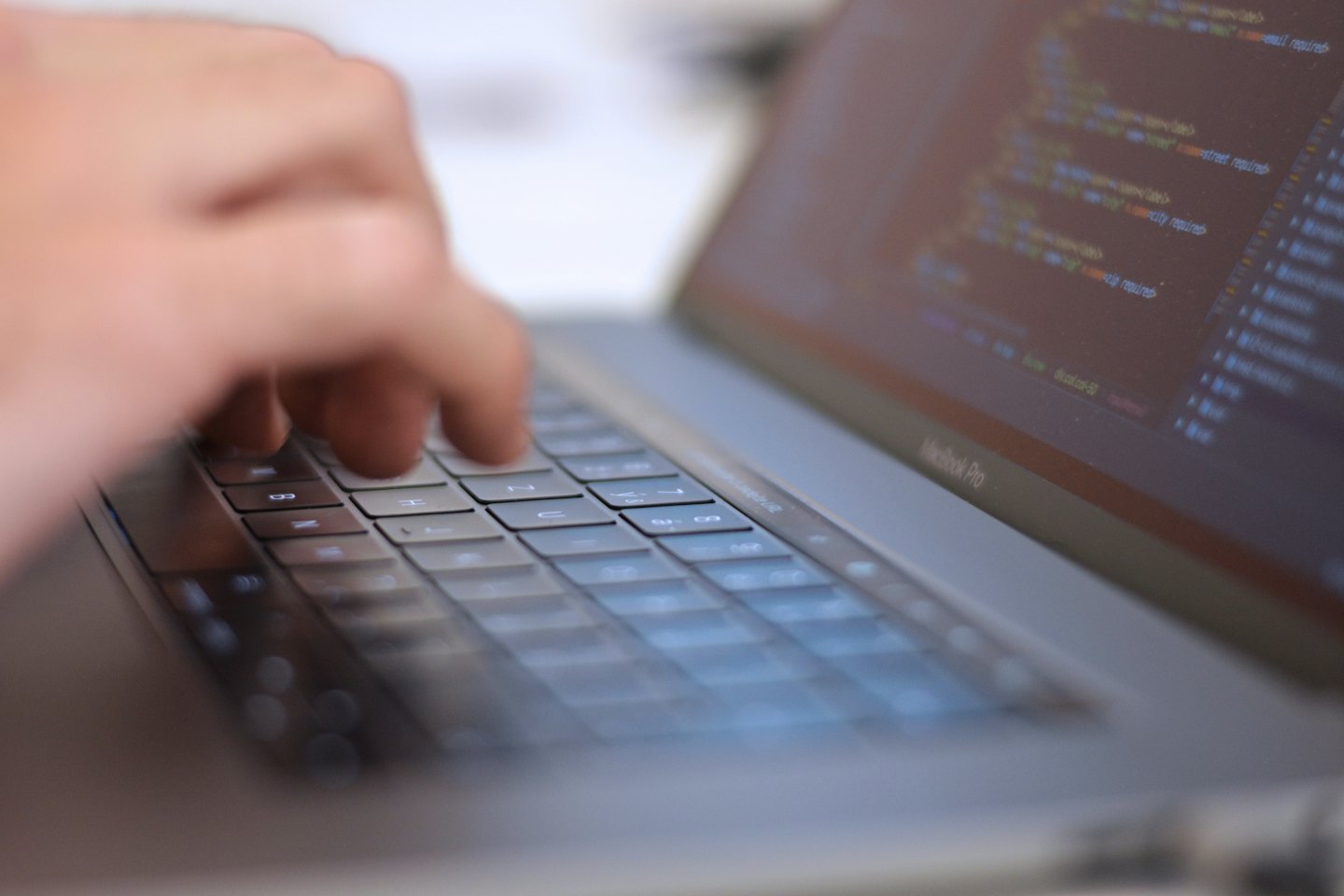 Manos escribiendo código de programación en el teclado de un portátil.